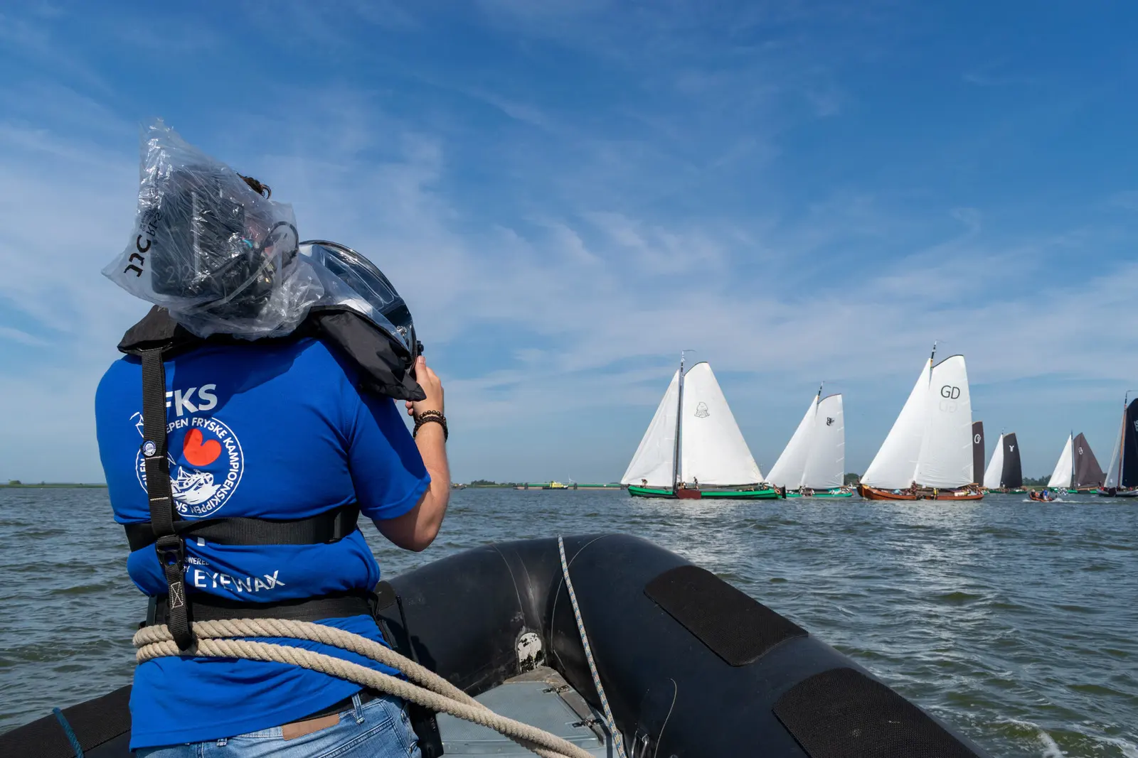 Cameraman op een rubberboot filmt de skûtsjes op het water