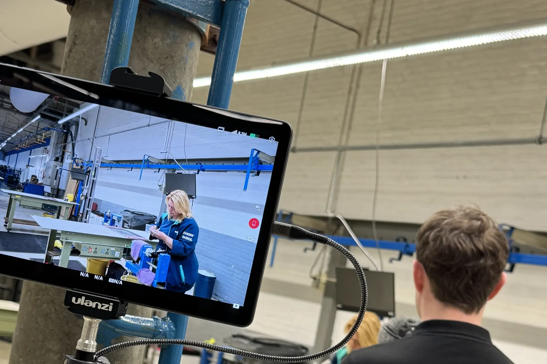 Crewlid van Eyewax kijkt mee op de monitor tijdens een interview in de fabriek
