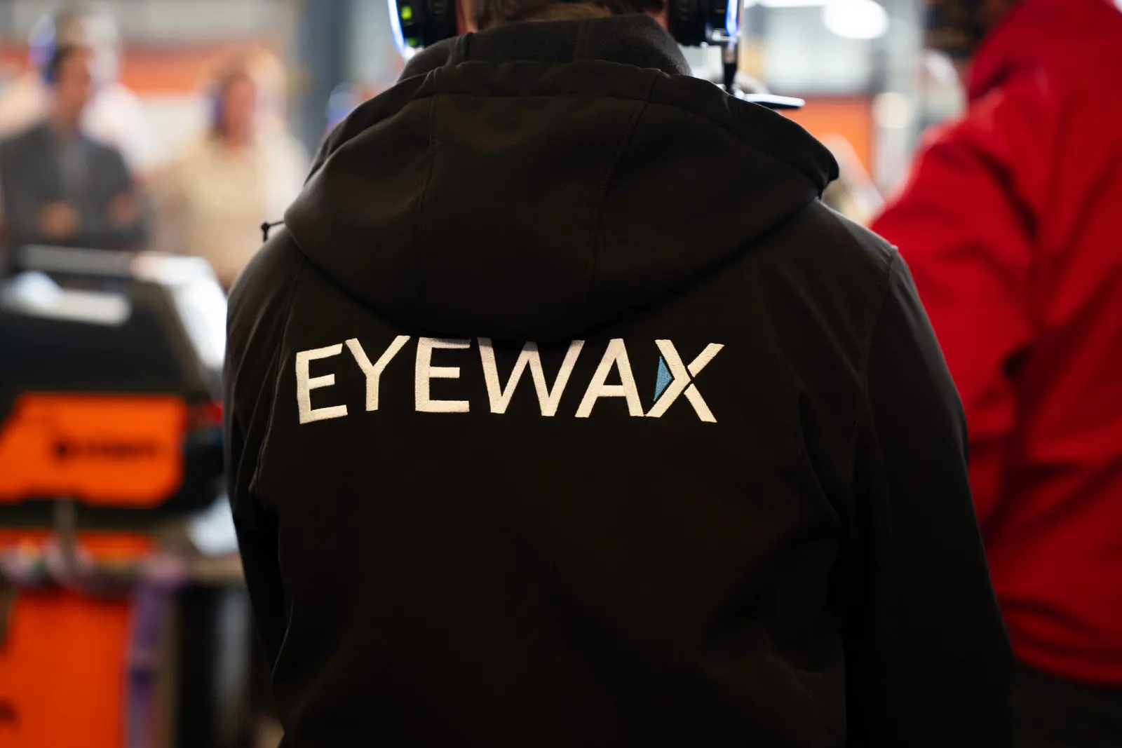 Crewlid in Eyewax-trui achter de camera tijdens een evenement
